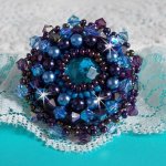 Bague Roses Bleues Royales brodée avec un cabochon facetté Bleu Roi à laquelle s'ajoute des perles nacrées, des toupies et de belles rocailles sur une bague laiton pour un style baroque